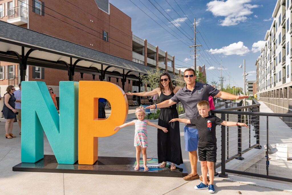 Family of 4 posing next to the NP letters